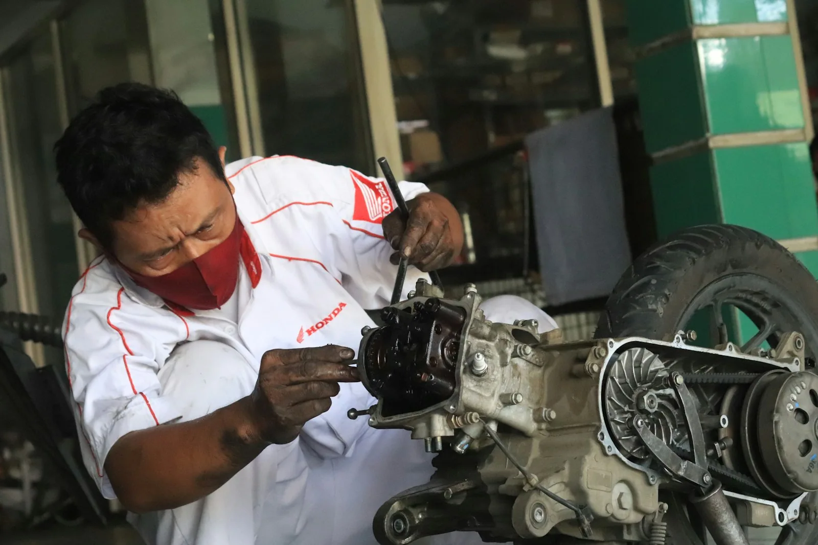 Teknisi merawat mesin sepeda motor di bengkel
